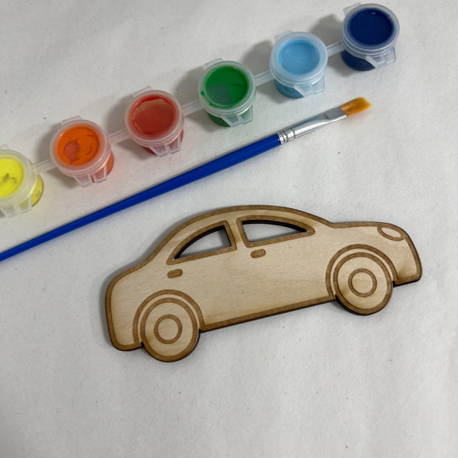 Wooden car-shaped object with paint containers and a brush on a white background