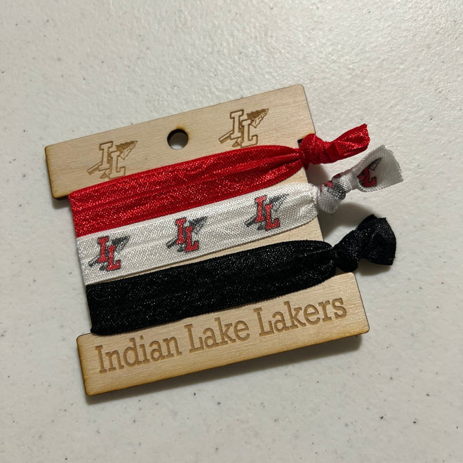 Three hair ties in red, white, and black with a branded tag on a light gray surface