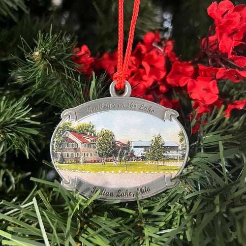 Decorative ornament with a scenic view of a house on a tree with red flowers.