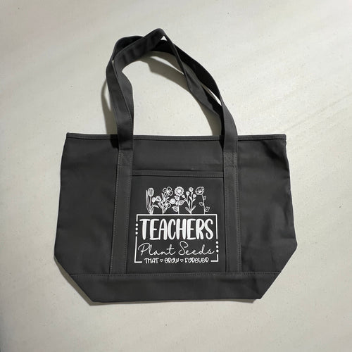 Black tote bag with white text and graphics on a white surface