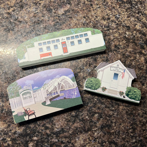 Three small decorative items resembling houses and a bridge on a granite surface