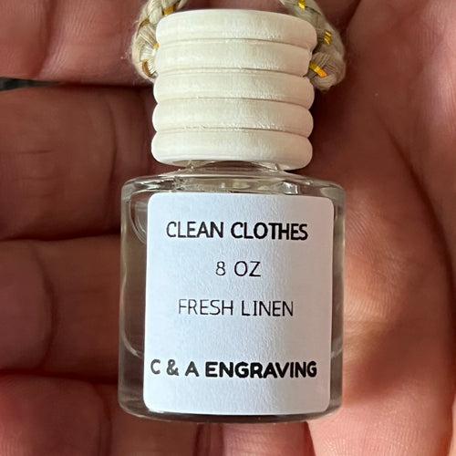 Small bottle labeled 'Clean Clothes Fresh Linen' held in a hand