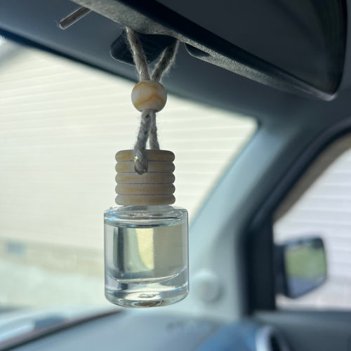 Car interior with a clear glass bottle hanging from the rearview mirror.