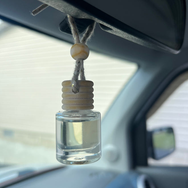 Car interior with a clear glass bottle hanging from the rearview mirror.