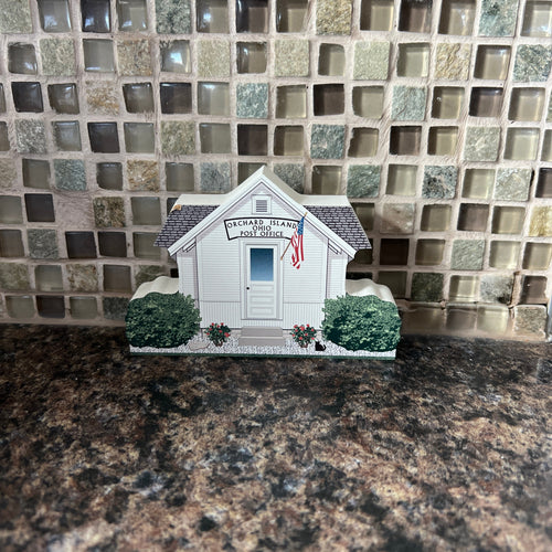 Small model house on a reflective surface with a textured background