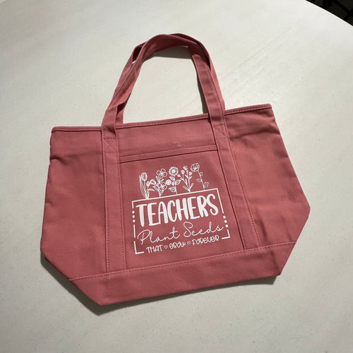 Rose colored tote bag with text on a white surface