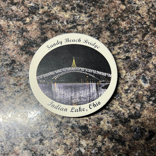 Circular coaster with a design of a lighted bridge on a granite surface
