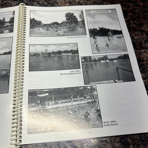 Spiral-bound book with black and white photographs on a textured surface