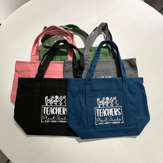 Five tote bags with 'Teacher' text on a round white background.