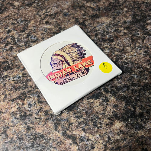 Colorful sticker on a white card with a yellow dot on a brown surface